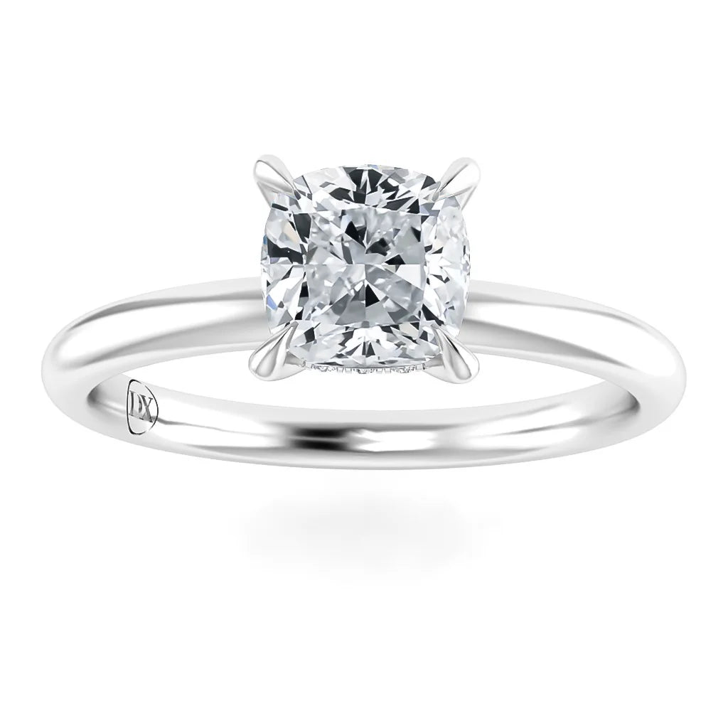 A silver engagement ring with a cushion-cut diamond solitaire set in four prongs on a plain band.