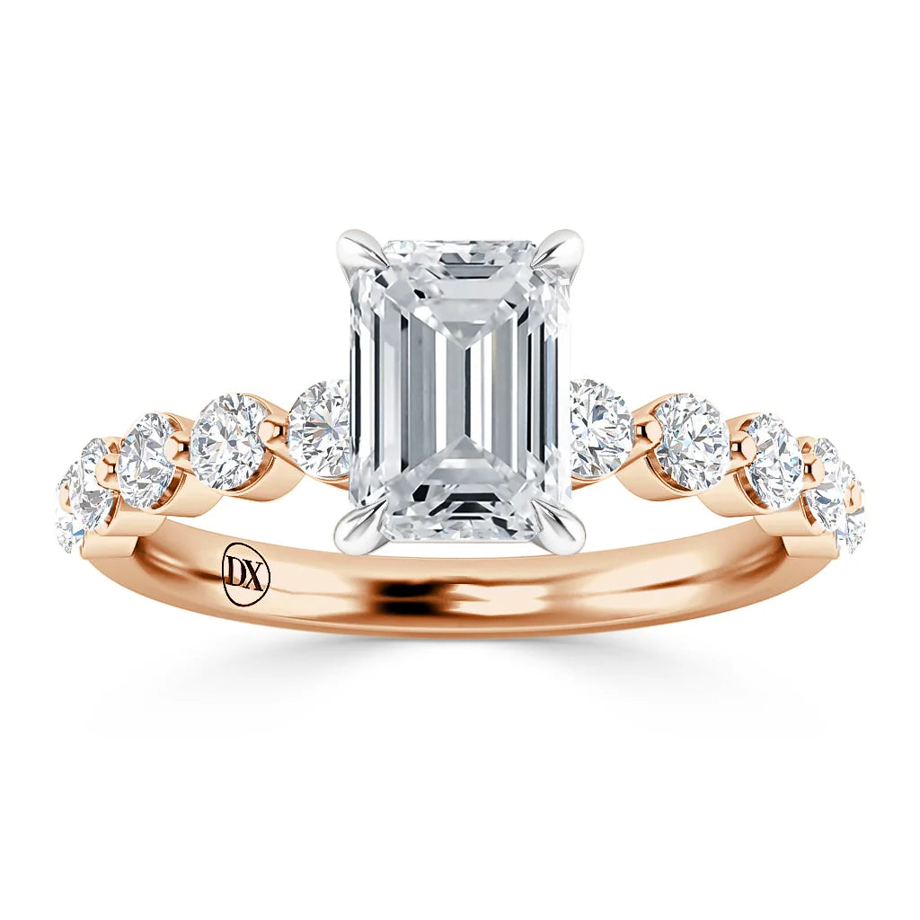 A rose gold ring with an emerald-cut center diamond and round diamonds along the band.