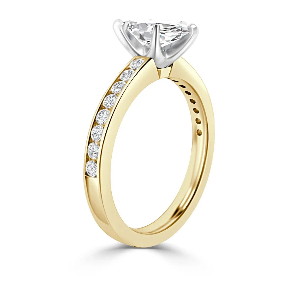 Gold ring with round diamonds on the band and a large solitaire diamond set in a white gold prong setting.