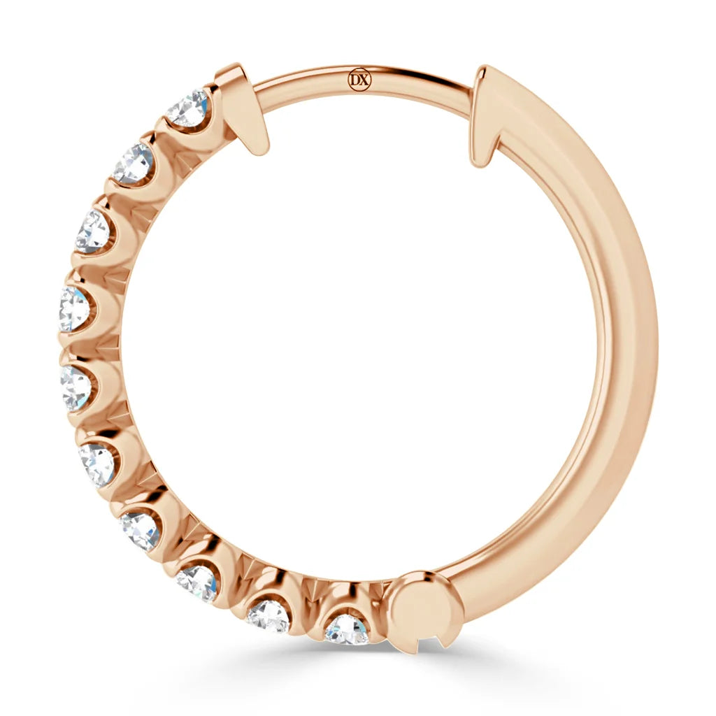 A rose gold hoop earring adorned with evenly spaced small white gemstones along half its edge.