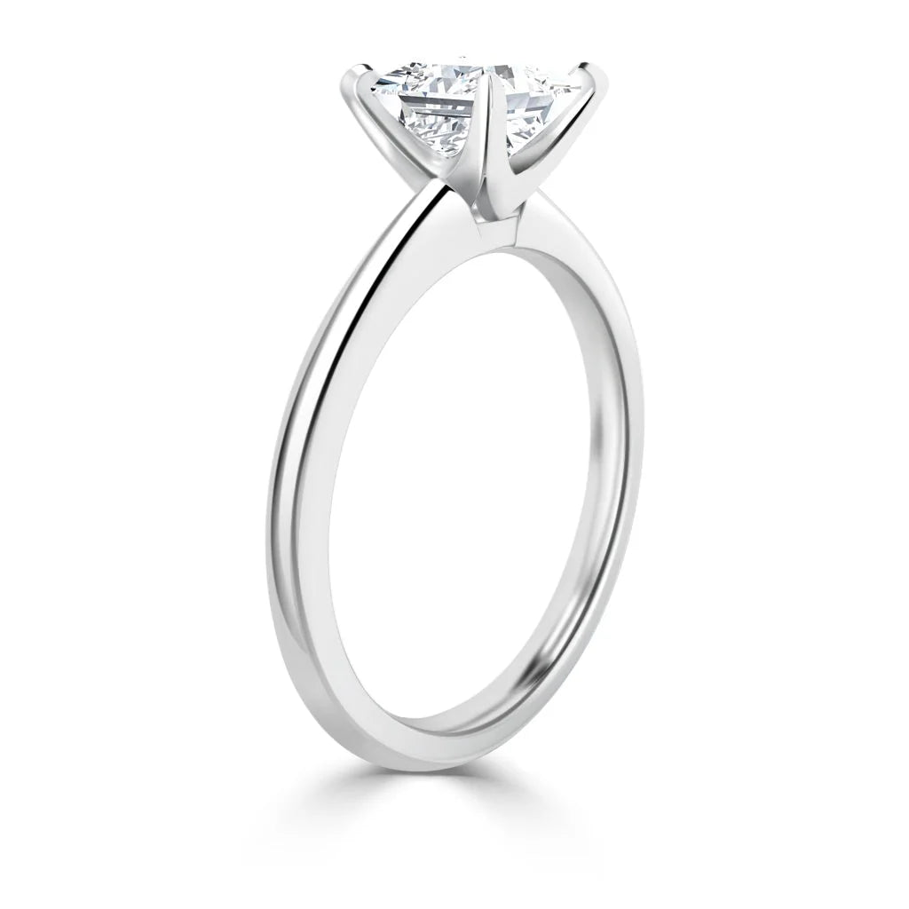 A silver solitaire engagement ring with a round-cut diamond in a four-prong setting, shown from the side.