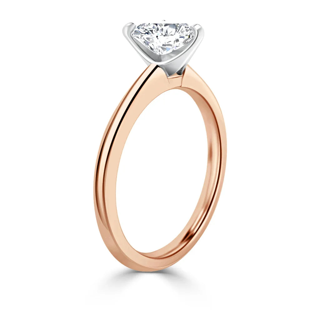 A rose gold ring with a single round diamond solitaire set in a white gold prong setting.