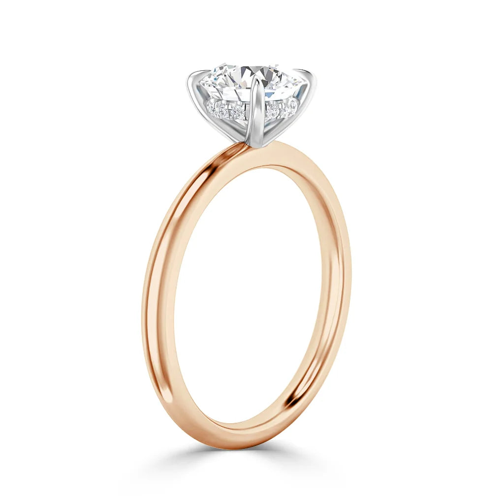 A rose gold ring with a round solitaire diamond set in a white gold prong setting, shown on a white background.
