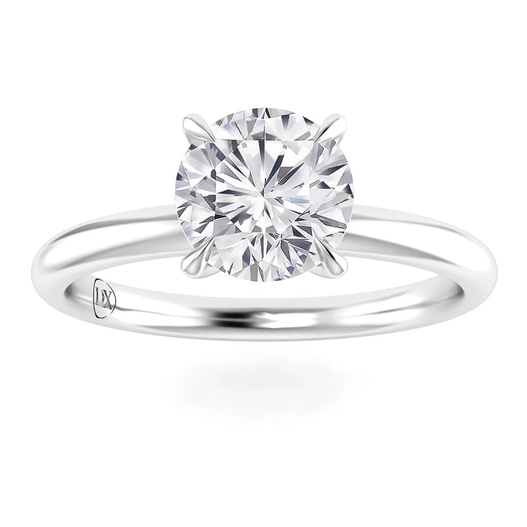 A round-cut diamond solitaire ring with a thin, shiny white metal band and four prongs holding the diamond.