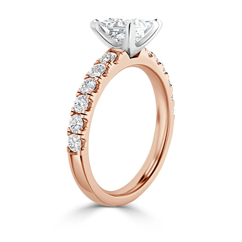Rose gold ring with round diamonds on the band and a large round diamond in a prong setting.