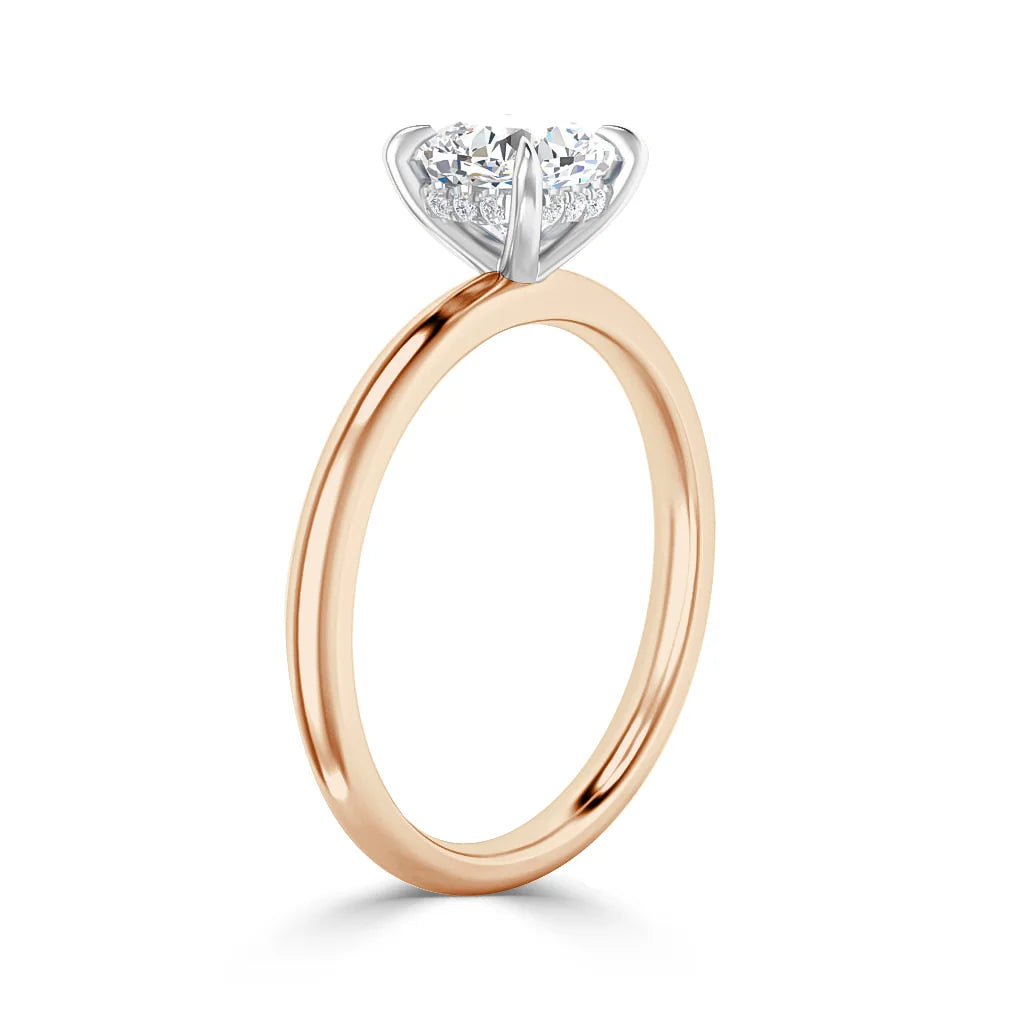 A rose gold ring with a round solitaire diamond set in a white gold prong setting, shown upright.