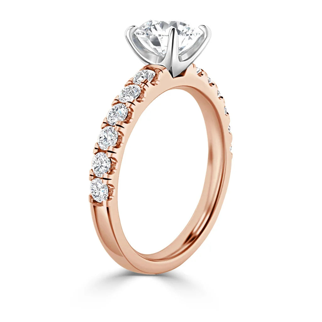 A rose gold ring with a round solitaire diamond and smaller diamonds set along the band.