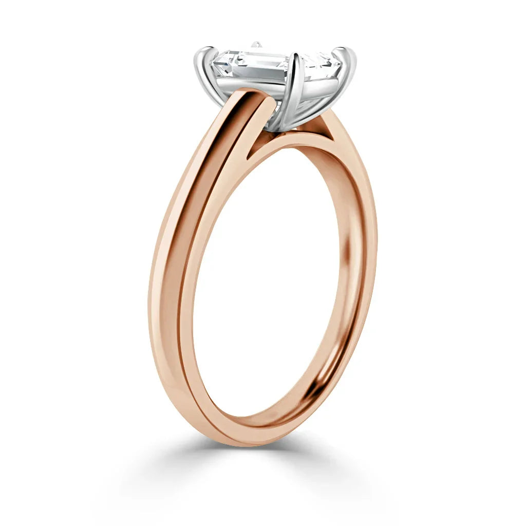 Rose gold band solitaire ring with a prong-set rectangular diamond in a white metal four-prong setting.