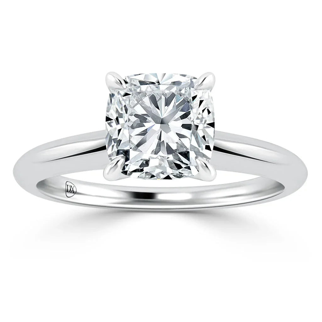 Cushion-cut diamond solitaire ring with a four-prong setting on a polished white metal band.