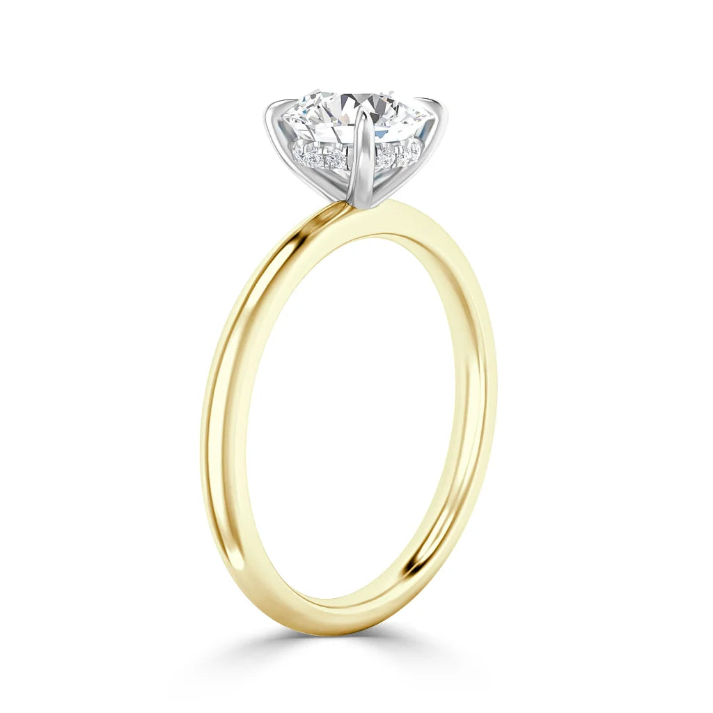 Gold band ring with a round diamond solitaire set in a white gold prong setting against a white background.