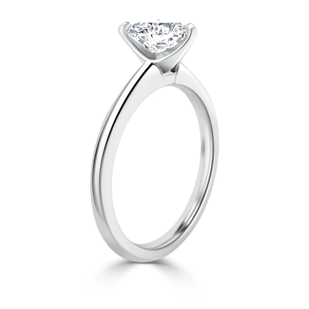 A silver solitaire ring with a round, prong-set diamond displayed on a plain, polished band.