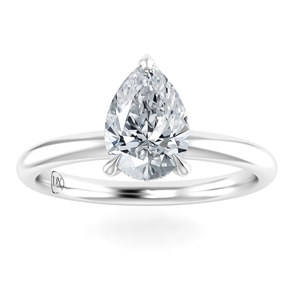 A pear-shaped diamond solitaire ring with a slim, polished white metal band on a white background.
