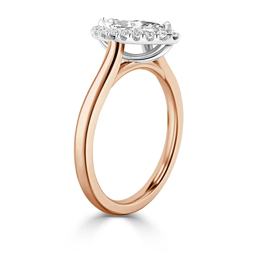 Rose gold ring with a round diamond halo setting and a thin, elegant band, shown from a side angle.