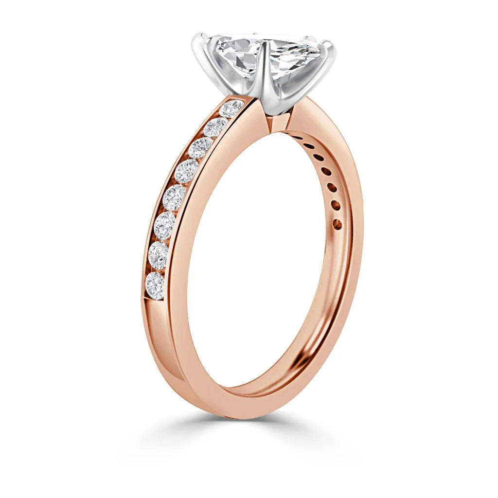 A rose gold ring with a large round diamond and smaller diamonds set along the band, on a white background.