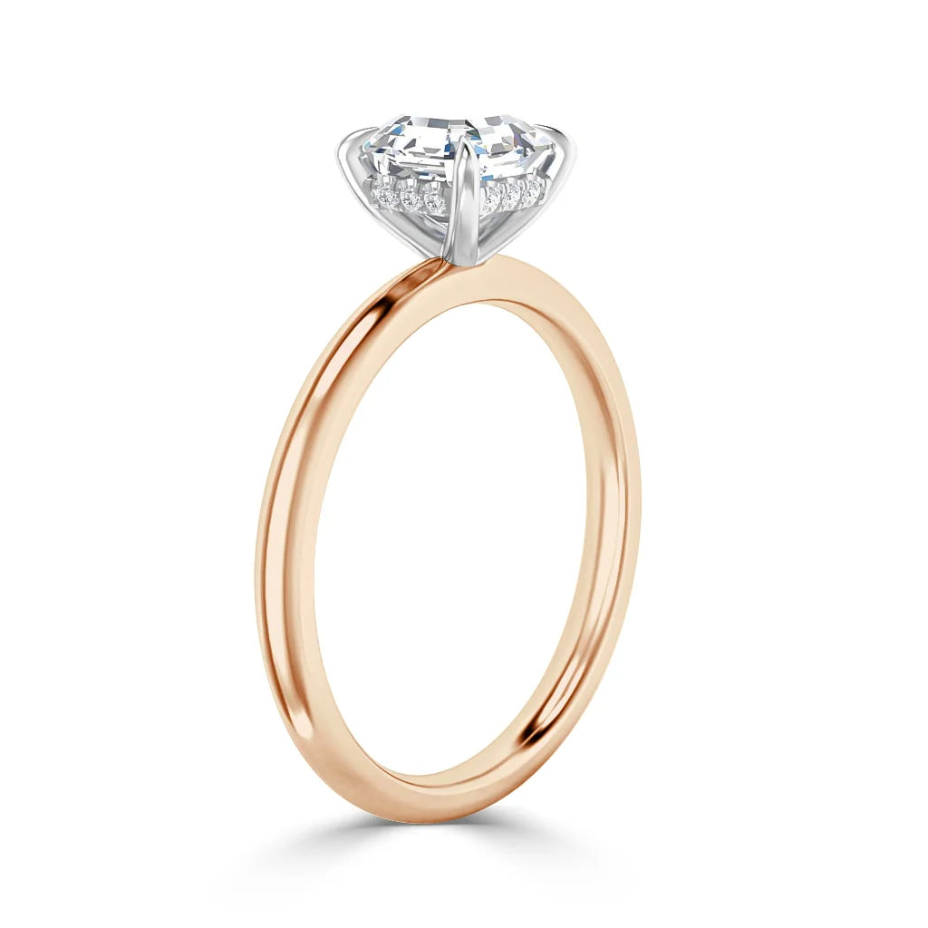 A gold solitaire ring with a round diamond held in a white gold prong setting, shown on a white background.