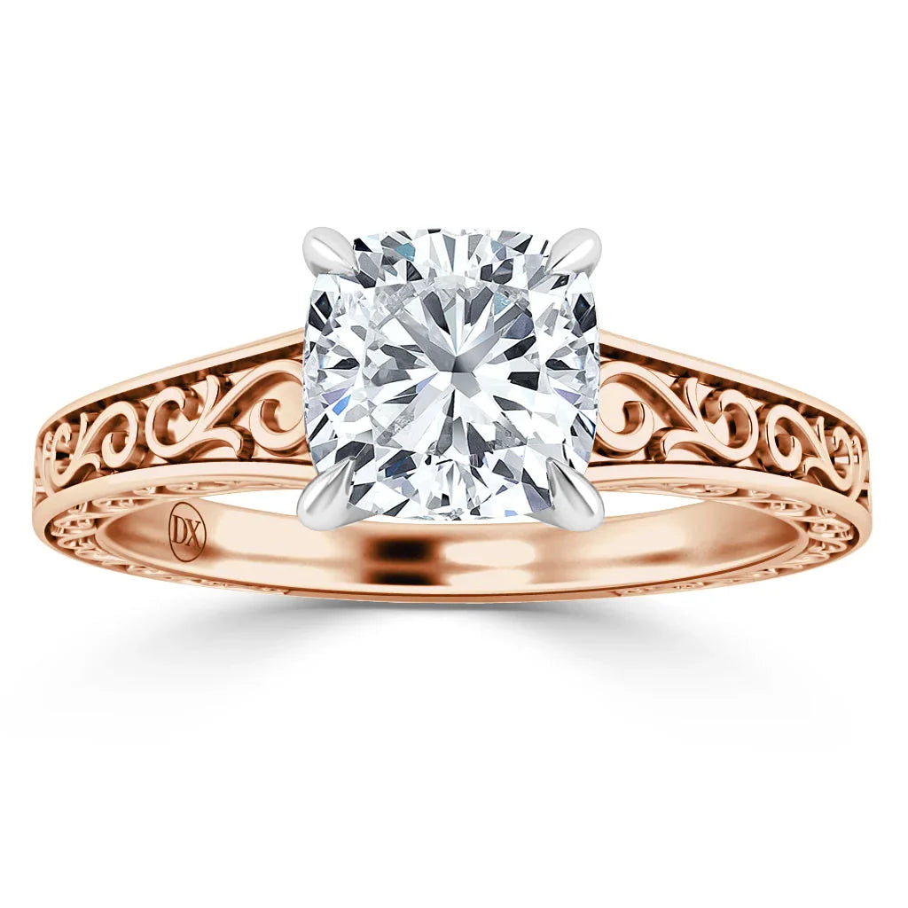 Rose gold ring with ornate filigree band and cushion-cut diamond in a four-prong white gold setting.