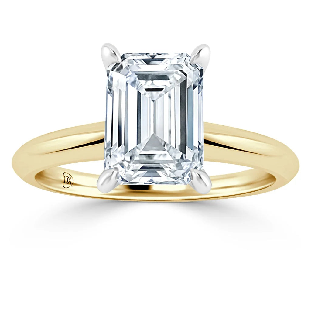 Gold band ring with a large emerald-cut diamond set in four prongs, shown on a white background.