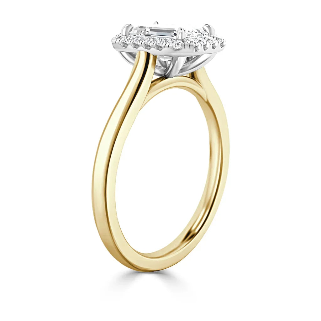 Yellow gold ring with diamond halo setting and a rectangular center stone, shown from a side angle.