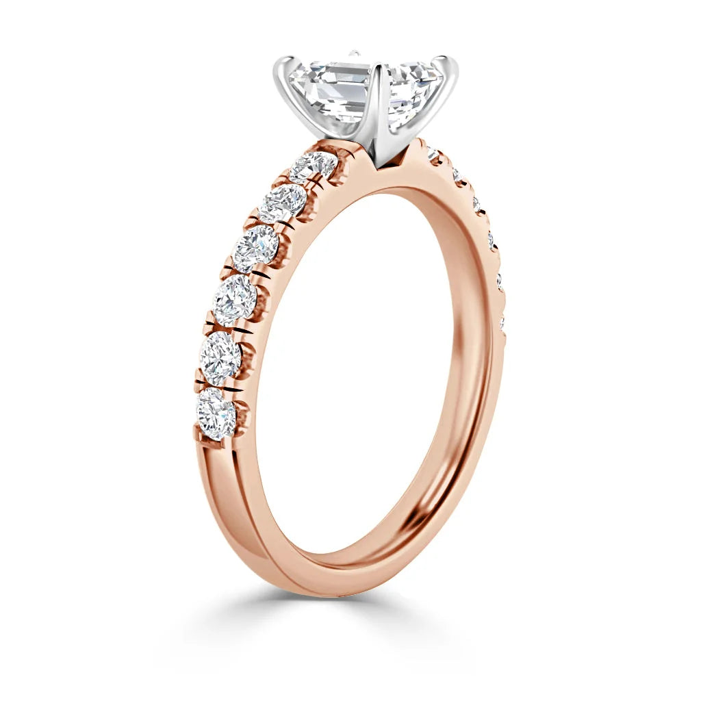 Rose gold engagement ring with round diamonds along the band and a large solitaire diamond in a prong setting.