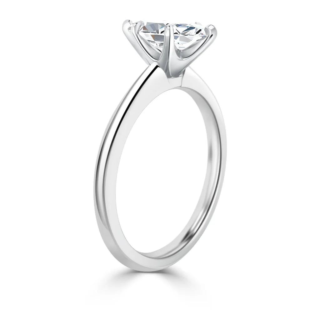 A silver solitaire engagement ring with a round, prong-set diamond displayed from a side angle.