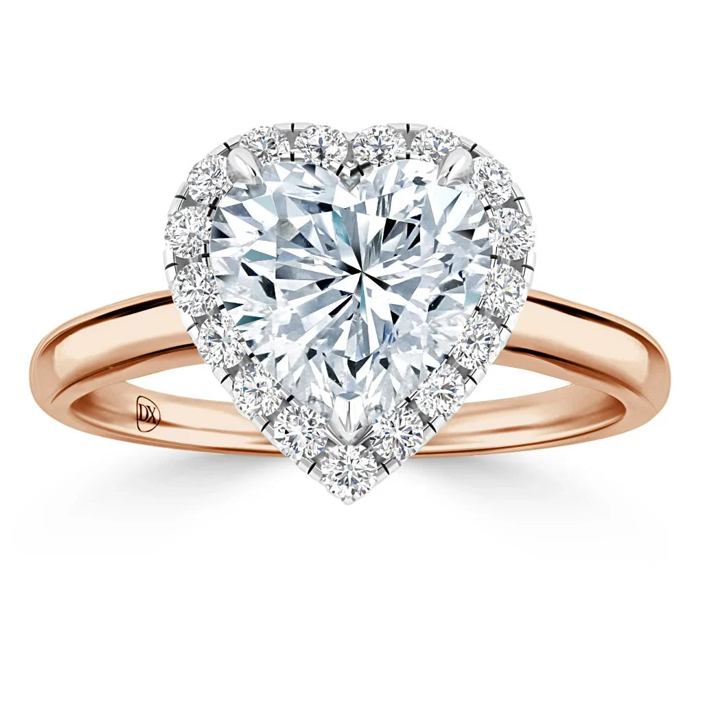 Heart-shaped diamond ring with a halo of smaller diamonds on a rose gold band, shown on a white background.