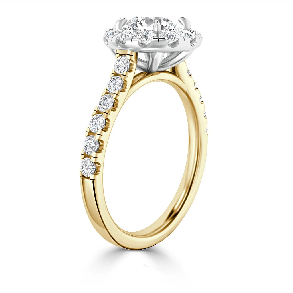 Gold engagement ring with round diamond center and smaller diamonds along the band, seen from a side angle.
