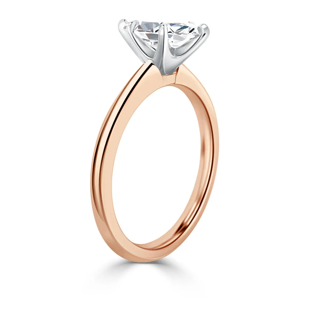 Rose gold ring with a round solitaire diamond set in a six-prong white gold setting, viewed from the side.