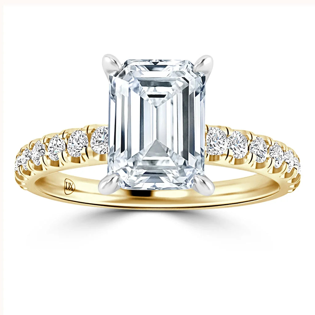 A gold ring with an emerald-cut diamond center and small round diamonds along the band.