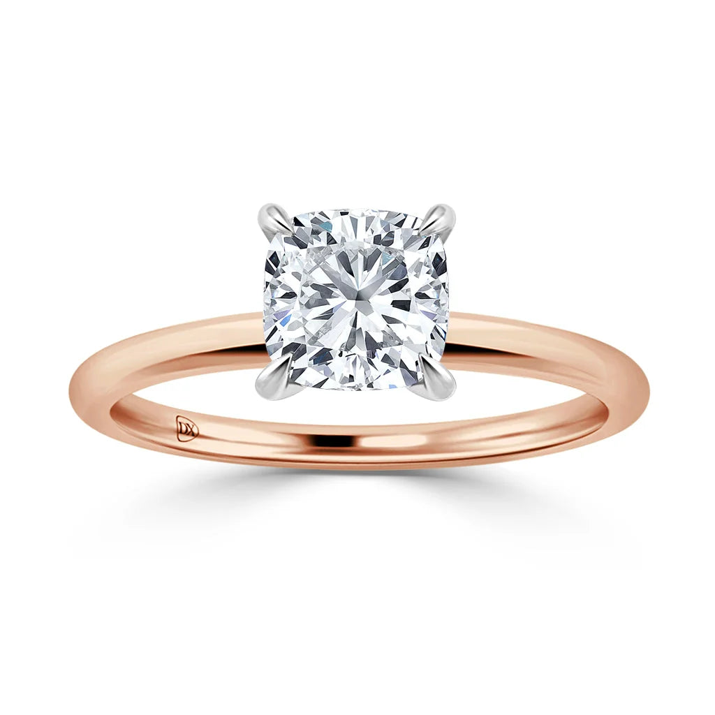 A rose gold ring with a single cushion-cut diamond in a four-prong white gold setting, shown on a white background.