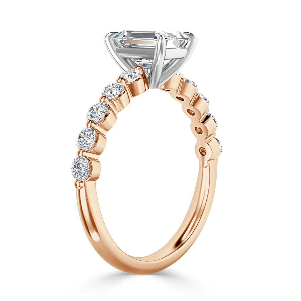 A rose gold ring with a large center diamond and round diamonds set along the band in a prong setting.