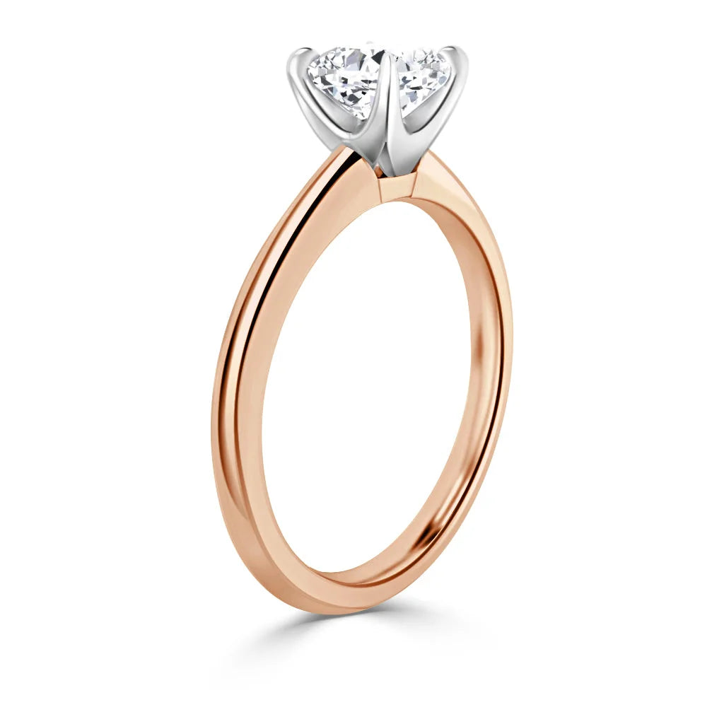 Rose gold ring with a round diamond solitaire in a white gold prong setting against a white background.