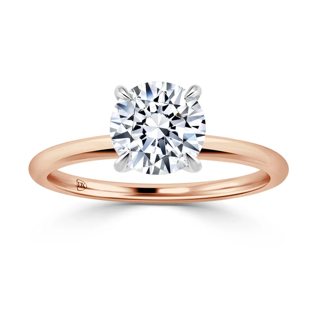A rose gold ring with a large round solitaire diamond held by four prongs, shown on a white background.