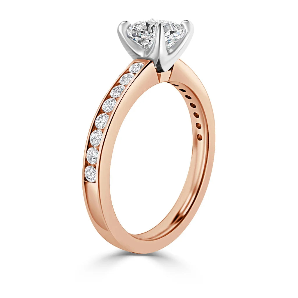 Rose gold ring with a round diamond center and side diamonds set along the band, prong setting visible.