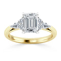 Emerald-cut diamond ring with side stones on a yellow gold band, viewed from the front.