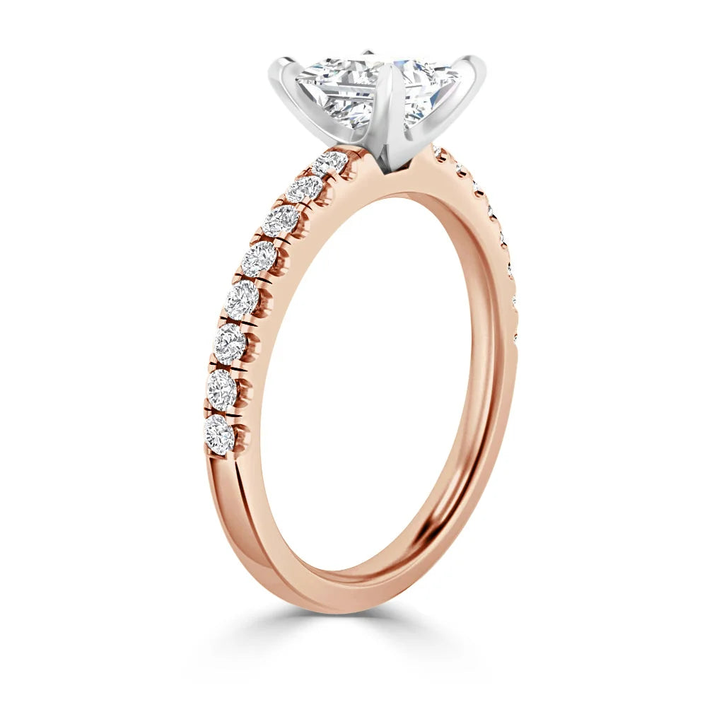 Rose gold ring with a row of small diamonds on the band and a large round diamond in a prong setting.