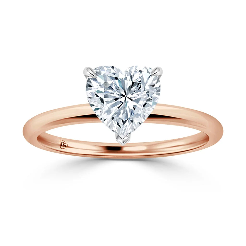 A rose gold ring with a heart-shaped diamond solitaire on a thin, polished band, shown on a white background.