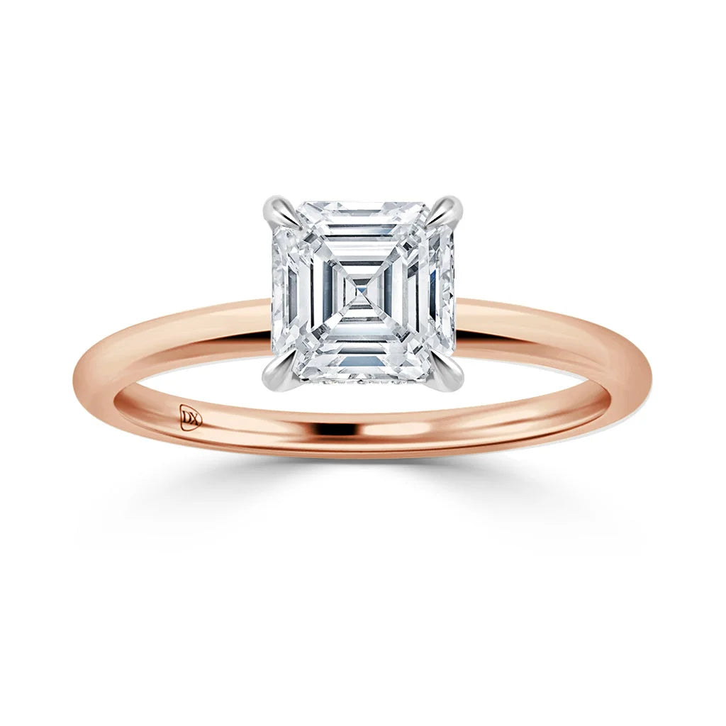 A rose gold ring with a square, asscher-cut diamond set in a four-prong white gold setting.