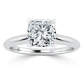 Platinum ring with a cushion-cut diamond solitaire set in four prongs on a plain band, shown on a white background.