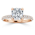 Rose gold ring with a cushion-cut diamond center and pavé diamonds on the band, shown against a white background.