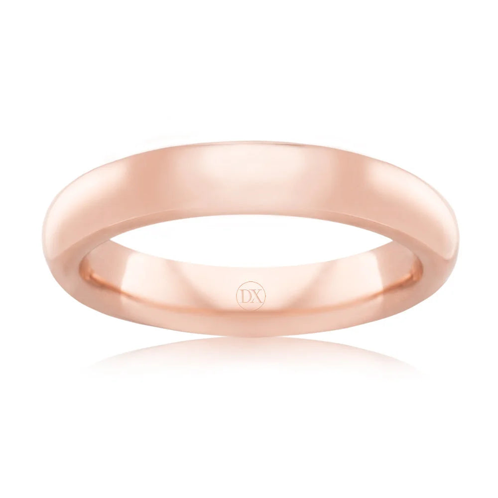 A simple, polished rose gold ring with a rounded band and a small DX engraving on the inner surface.