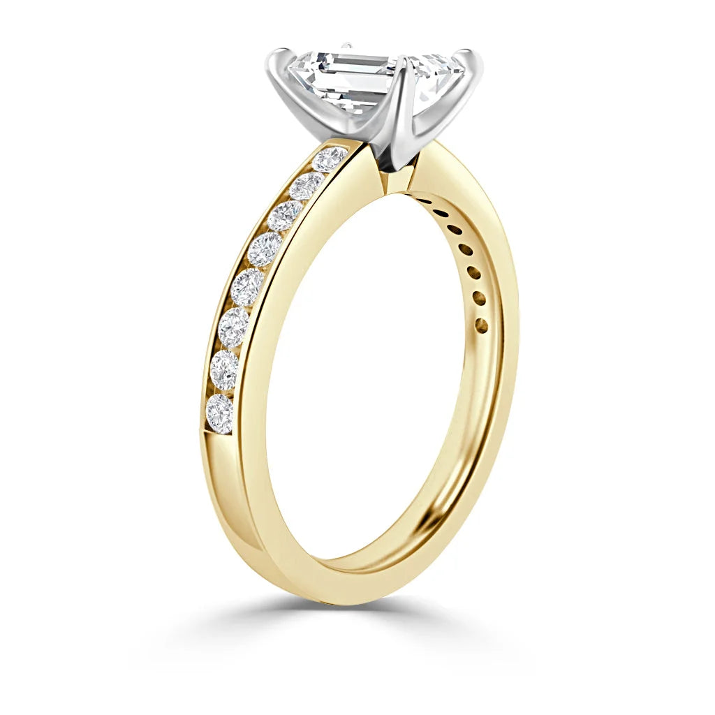 A gold ring with side diamonds and a large emerald-cut center stone in a white prong setting.
