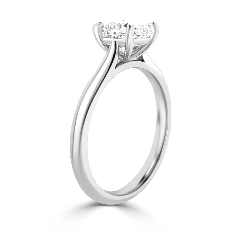 A white gold solitaire engagement ring with a round diamond in a four-prong setting, shown from the side.
