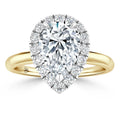 A gold ring with a large pear-shaped diamond center, surrounded by a halo of smaller round diamonds.