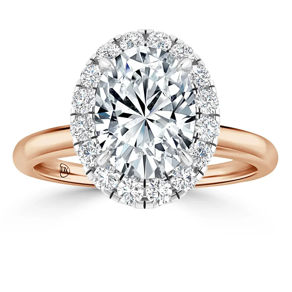 Oval diamond ring with a halo of smaller diamonds on a rose gold band, shown on a white background.