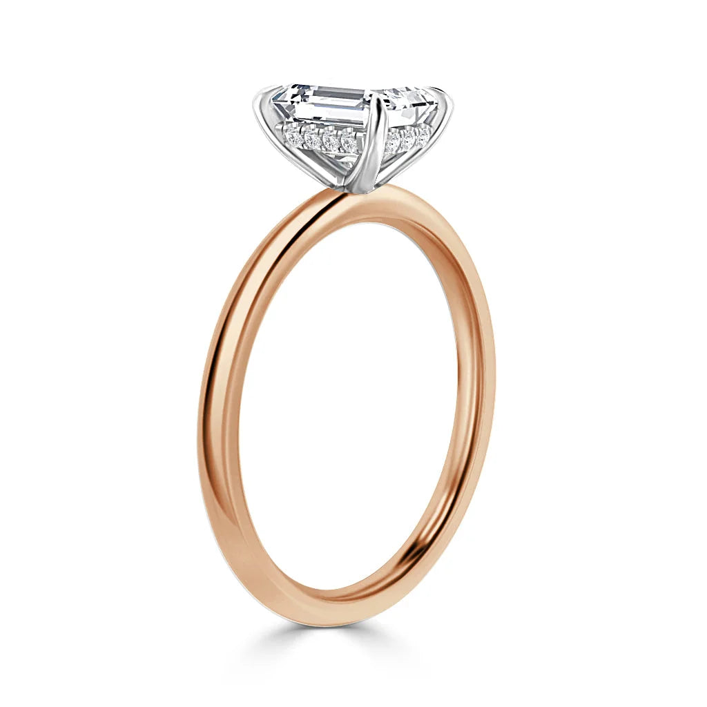 A rose gold ring with a raised white gold setting featuring a rectangular diamond and smaller accent diamonds.