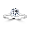 A silver ring with a round, brilliant-cut diamond solitaire in a four-prong setting on a plain band.