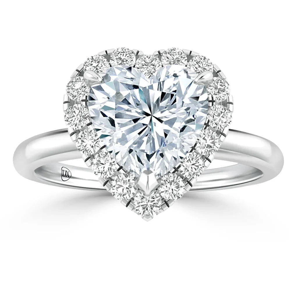 Heart-shaped diamond ring with a halo of smaller diamonds on a silver band, set against a white background.