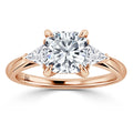 Rose gold ring with a large round diamond center and two triangular side diamonds on a plain band.