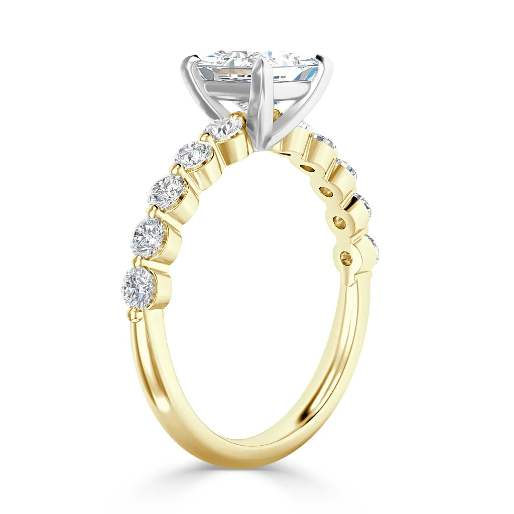 A gold ring with round diamonds on the band and a large raised center stone in a white gold prong setting.
