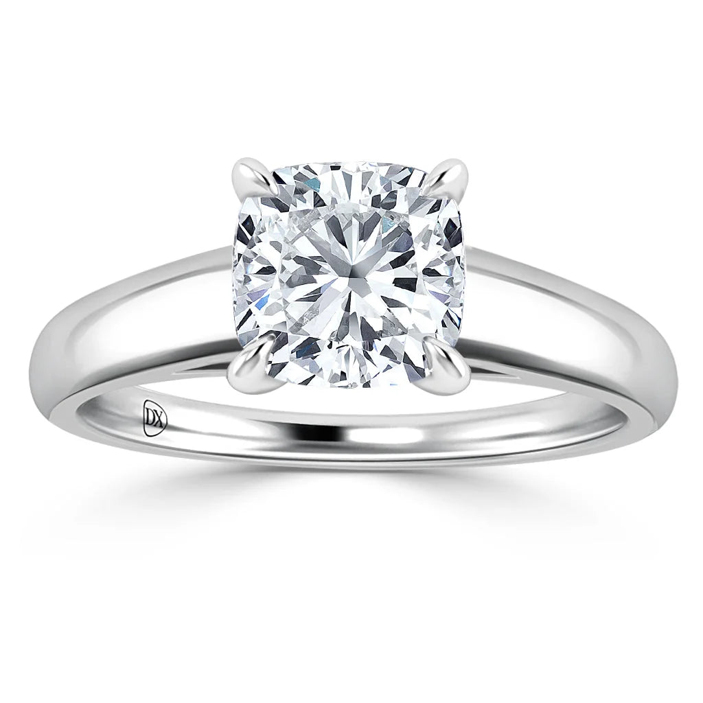 A silver ring with a cushion-cut diamond solitaire set in four prongs on a plain polished band.